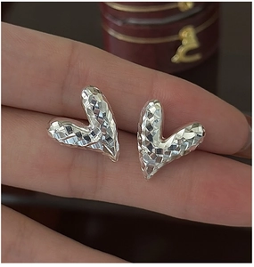 Vue macro des boucles d'oreilles cœur en argent S925 avec texture facettée