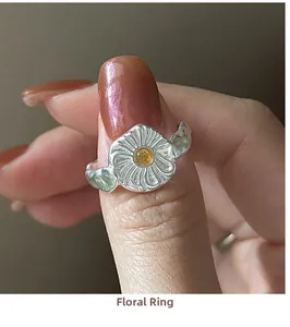 Macro detail of a sterling silver daisy flower ring with a bright yellow crystal center