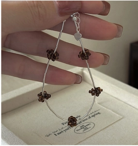 Detail of vintage S925 silver beaded bracelet with brown floral charms and heart pendant