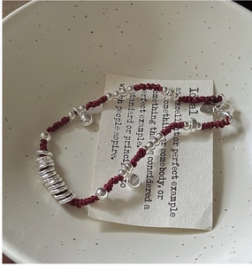 Dettaglio dei ciondoli in argento S925 e del pendente a cuore su un braccialetto rosso
