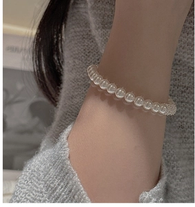 Gros plan sur un bracelet en perles blanches élégant doté d'un fermoir rond serti de cristaux