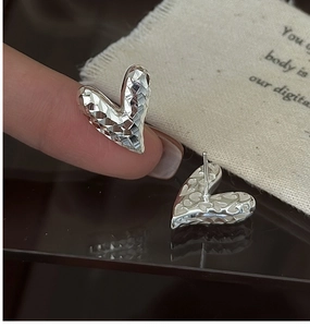 Vue macro de boucles d'oreilles cœur en argent 925 avec texture facettée brillante