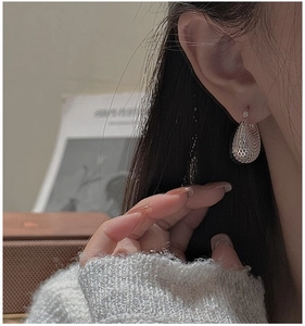 Gros plan d'un modèle portant des boucles d'oreilles goutte en argent S925 évidé
