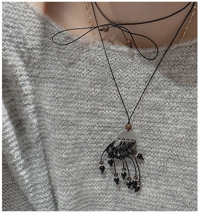 Détail du collier à pampilles en argent S925 avec nœud sur un pull gris