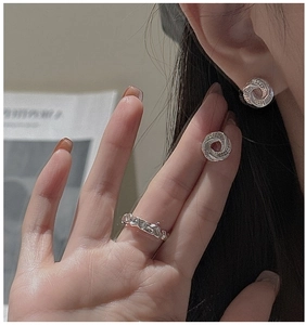 Detail of silver S925 earrings and textured ring worn by a model in a minimalist style