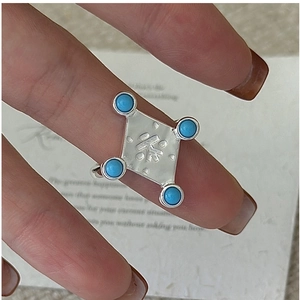 Macro shot of silver ring featuring square tea character engraving and turquoise accents
