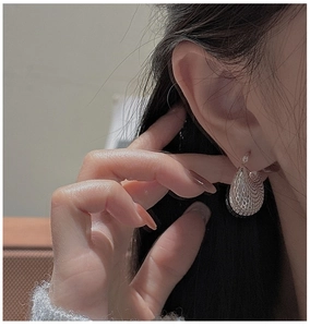 Détail d'une boucle d'oreille goutte d'argent avec motif quadrillé sur un mannequin