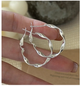 Macro shot of S925 sterling silver hoop earrings featuring a wavy twisted texture design