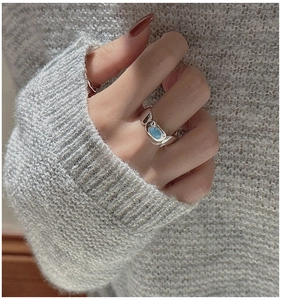 Detail of vintage silver ring with oval turquoise stone on gray knit sweater background