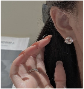 Detail of silver spiral stud earrings and wavy ring on a model with lifestyle background