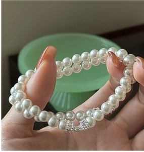 Détail du bracelet double rang de perles blanches avec fermoir nœud argenté fin