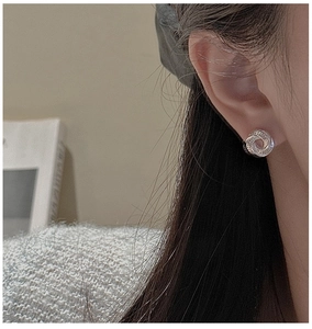Close-up of S925 sterling silver hollow swirl stud earrings worn on model ear