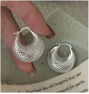Gros plan sur les boucles d'oreilles boules évidées en argent S925 avec poinçon gravé