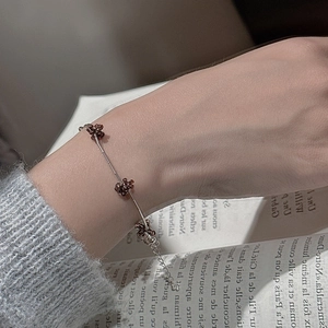S925 sterling silver beaded bracelet with burgundy flower on wrist over a grey sweater