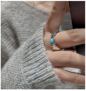 Macro detail of S925 silver ring featuring an oval turquoise stone on a gray knit sweater