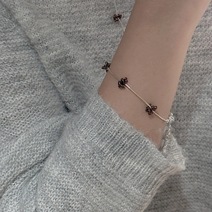 Minimalist S925 silver beaded flower bracelet worn over a grey knit sweater
