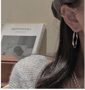 Detail of wavy S925 sterling silver drop earring and ear cuff on a female model