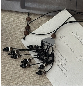 Détail d'un pendentif bohème en argent S925 fait main avec perles en bois et corde tissée