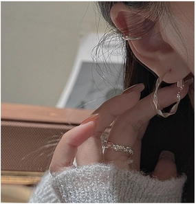 Detail view of wavy silver earrings and ring set on model with minimalist styling