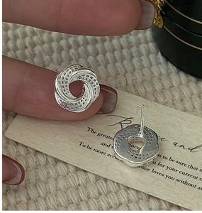 Macro shot of S925 silver earrings with intricate 3D hollow mesh and twisted design