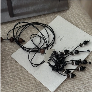 Détail d'un collier pull vintage tissé à la main avec glands noirs et perles