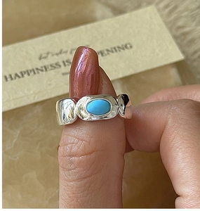 Detail of vintage silver ring featuring wide wavy band and oval turquoise gemstone inlay