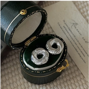 Detail of silver twisted texture earrings placed in a vintage green velvet jewelry box
