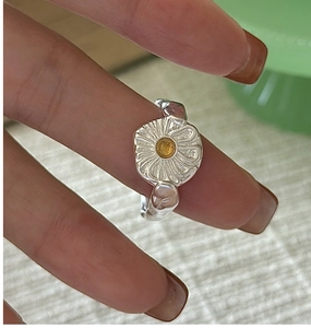 Close-up of S925 silver daisy ring with yellow crystal core on model's finger