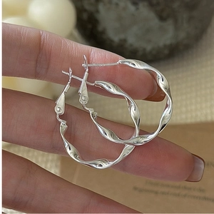 Macro detail of S925 sterling silver hoop earrings with a twisted rope design and hallmark