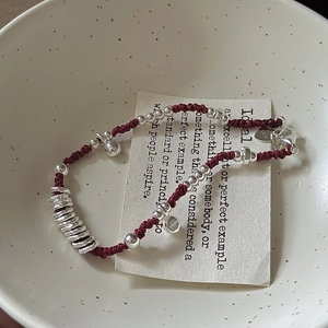 Bracciale minimalista in argento sterling S925 con cordino rosso in una ciotola di ceramica
