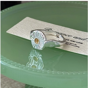 Macro shot of S925 sterling silver daisy ring with gold pistil and textured petals