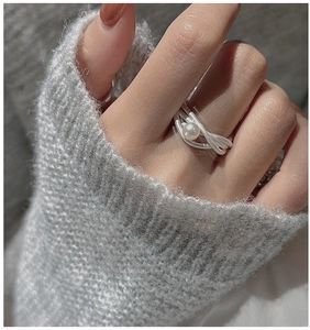 Dettaglio dell'anello in argento S925 satinato con perla bianca su sfondo in maglia