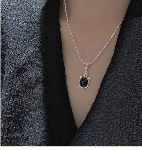 Détail d'un pendentif tortue en argent S925 avec une pierre noire sur une chaîne fine