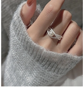 Dettaglio anello in argento S925 multistrato con perla bianca su sfondo in maglia
