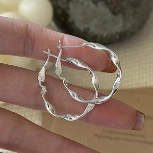 Handheld view of S925 sterling silver twisted hoop earrings with a minimalist wavy design