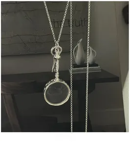 Detail of vintage silver magnifying glass pendant with search for the truth quote decoration