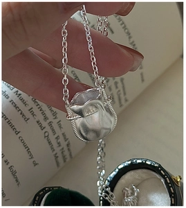 Gros plan du pendentif sac de chance en argent S925 sur une boîte à bijoux en velours vert