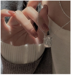 Vue détaillée du collier pendentif sac porte-bonheur en argent S925 sur un pull blanc