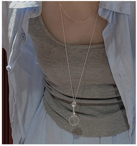 Close-up of a double-layered S925 silver necklace with round pendant on casual outfit