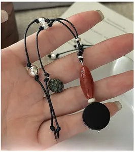 Detail of handcrafted beaded necklace with black cord, silver beads and green agate stone