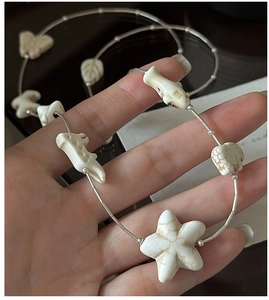 Close-up of S925 sterling silver long necklace with carved white charms of starfish and elephant