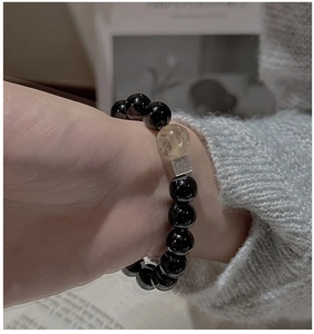 Close-up of S925 silver bracelet with black agate beads and rutilated quartz on a wrist