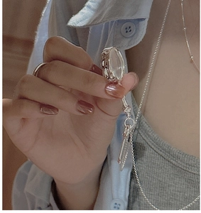 Close-up of vintage silver magnifying glass pendant with embossed texture on long chain