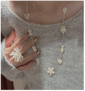 Detailed view of silver long necklace with white animal charms and bead cluster ring