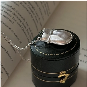 Détail macro du pendentif visage argenté sur boîte en cuir avec fond de livre rétro