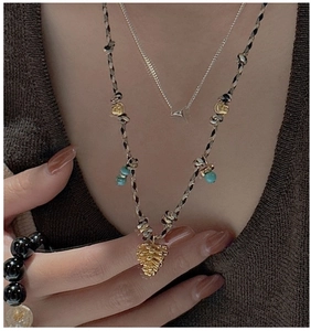 Détail du collier en corde tressée vintage avec perles turquoise et pendentif pomme de pin