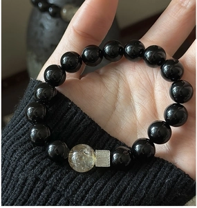 Macro detail of S925 silver black agate bracelet with rutilated quartz on a wrist