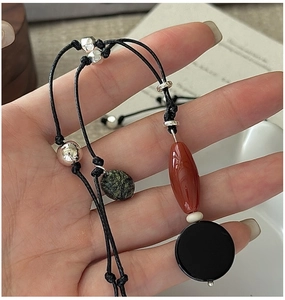 Detail of handmade black cord necklace with silver beads and green agate stone pendant