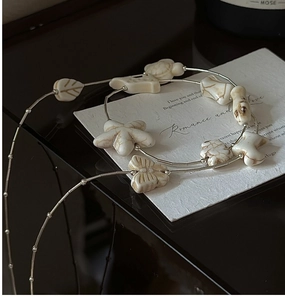 Macro detail of silver beaded chain and white marble-textured pendants with elegant reflection