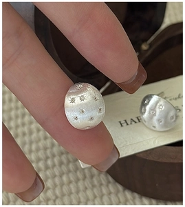 Detail of S925 sterling silver stud earrings with brushed texture and star pattern